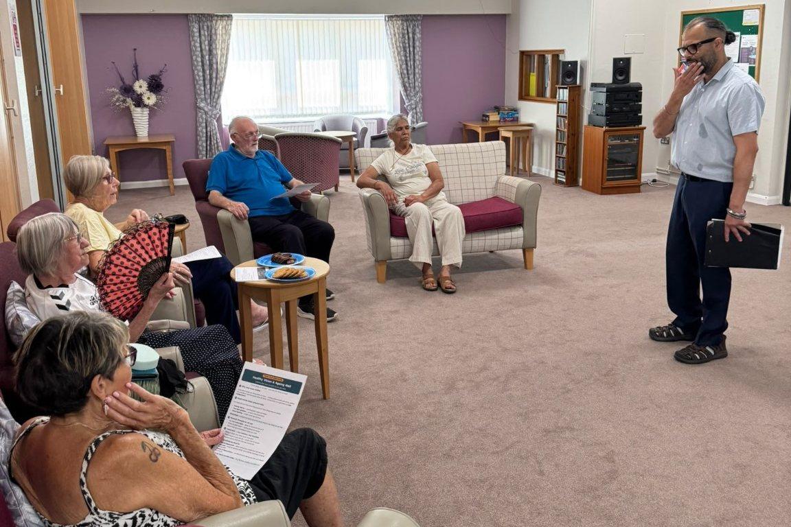 Residents seated with printed handouts during a Healthy Vision and Ageing Well talk